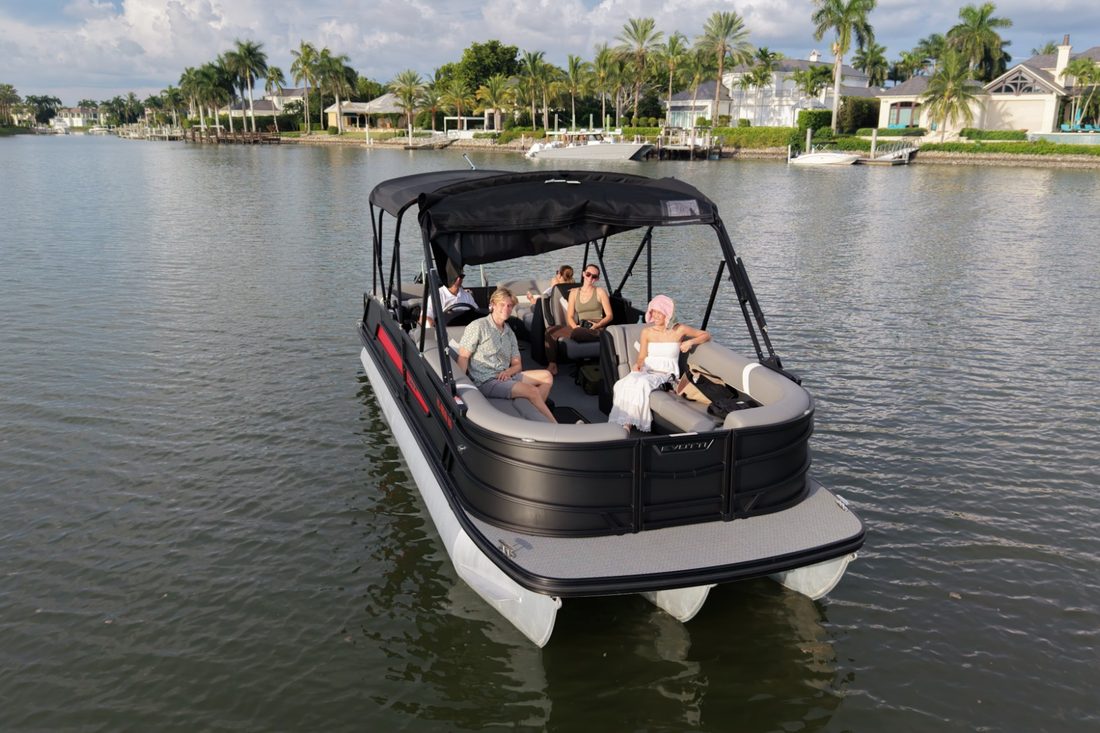 The Evotti luxury pontoon from the Sand Dollar fleet with guests aboard on a canal lined with waterfront homes