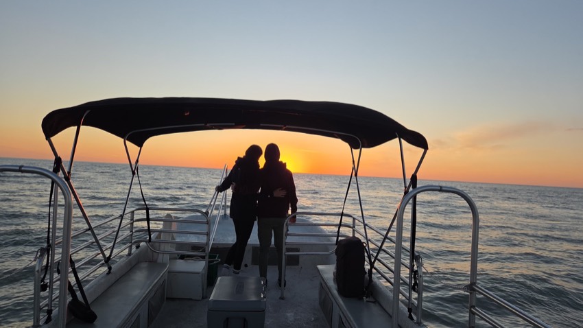 A couple silhouetted on the bow against a golden Gulf sunset on a Sand Dollar private charter, Marco Island