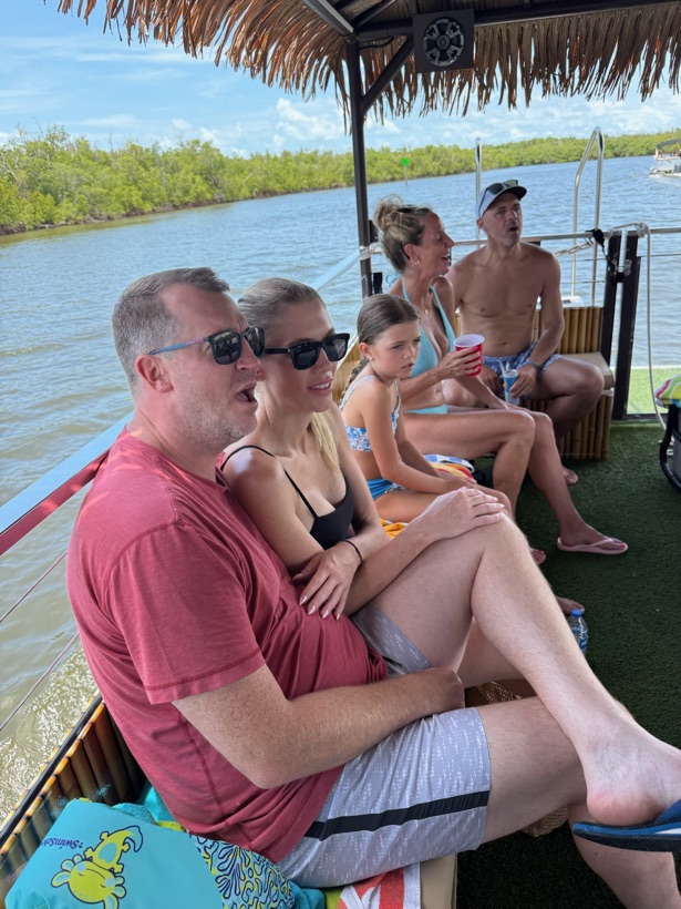 Guests with snacks and drinks relaxing on the Sand Dollar tiki boat near Naples